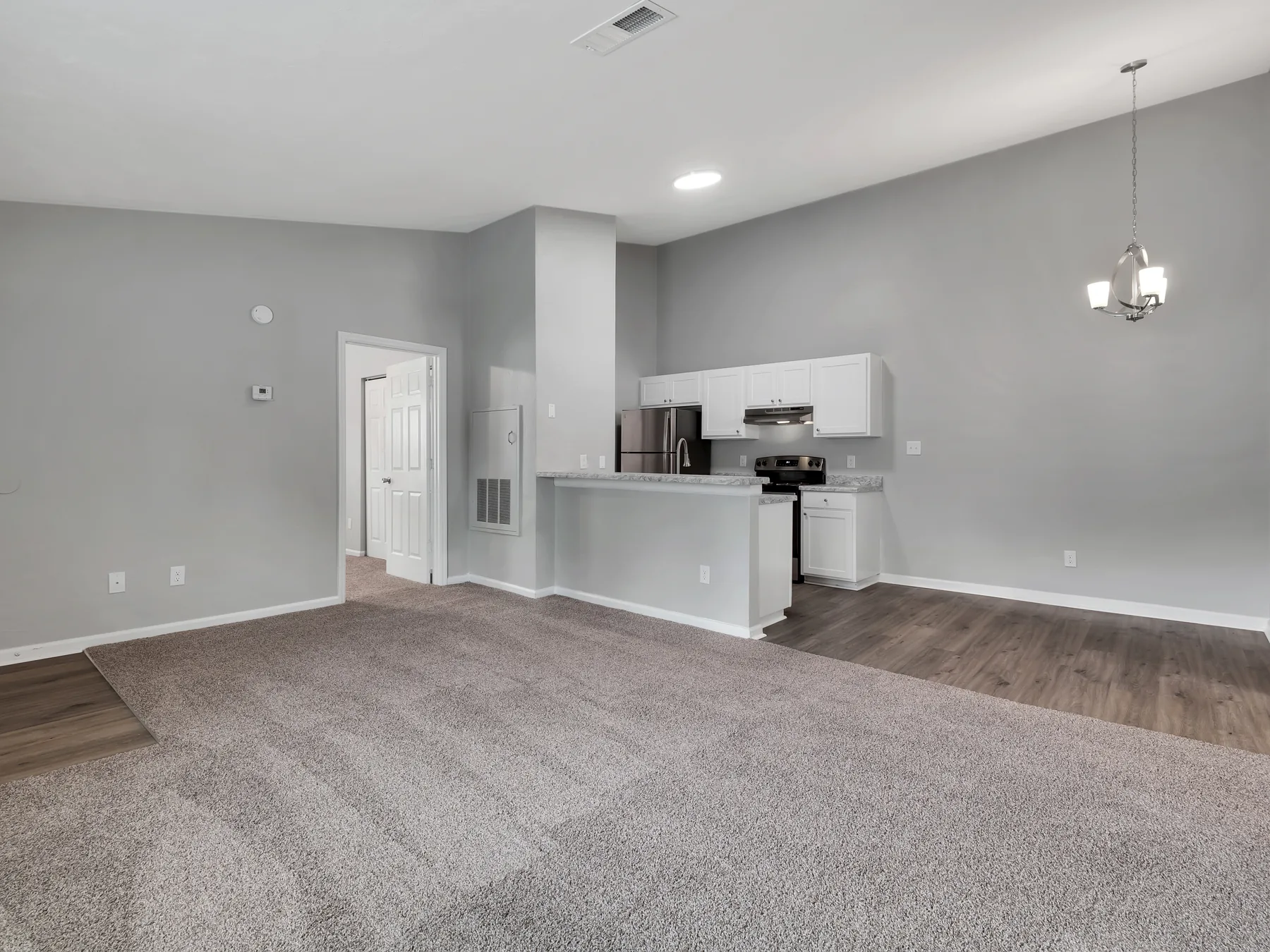 Living room and kitchen with vaulted ceiling and breakfast bar at Crescent Ridge Apartments
