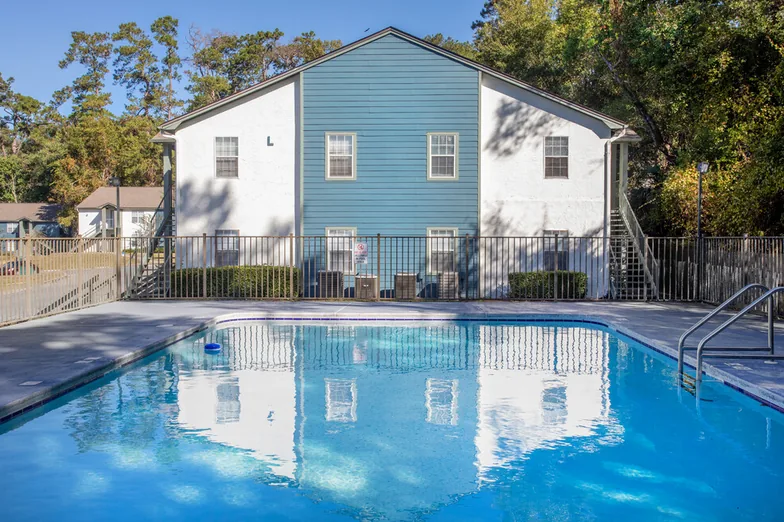 Swimming pool with fenced deck in front of a two-story apartment building at Crescent Ridge, Tallahassee